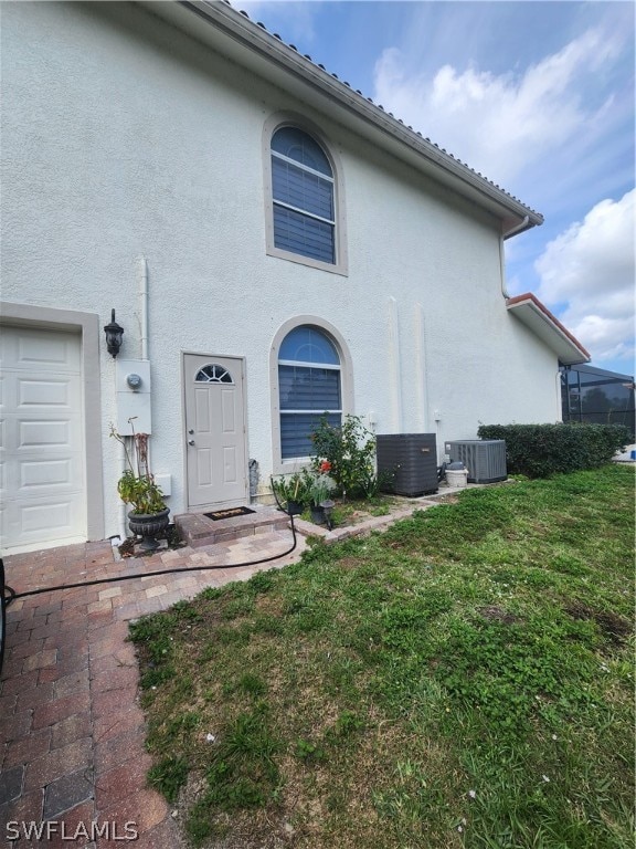 exterior space with central air condition unit, a yard, and a garage