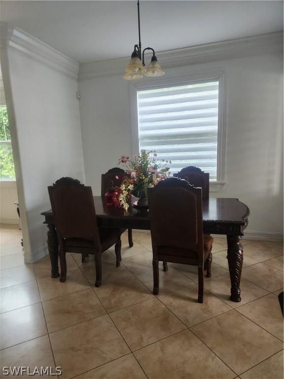 dining area featuring crown molding, light tile patterned flooring, a healthy amount of sunlight, and an inviting chandelier