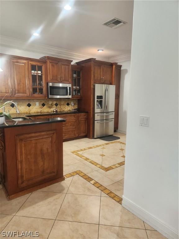 kitchen with sink, stainless steel appliances, tasteful backsplash, light tile patterned floors, and ornamental molding