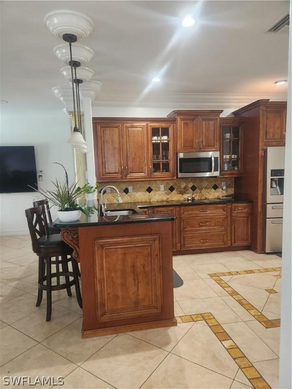 kitchen featuring tasteful backsplash, stainless steel appliances, sink, light tile patterned floors, and decorative light fixtures