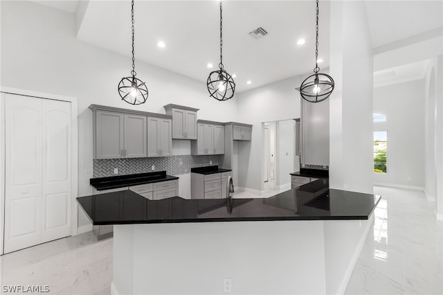 kitchen with decorative light fixtures, light tile flooring, a high ceiling, tasteful backsplash, and gray cabinetry