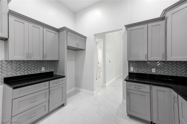 kitchen featuring tasteful backsplash, gray cabinetry, light tile floors, and dark stone counters