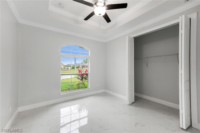 unfurnished bedroom featuring a closet, ceiling fan, light tile flooring, a tray ceiling, and crown molding