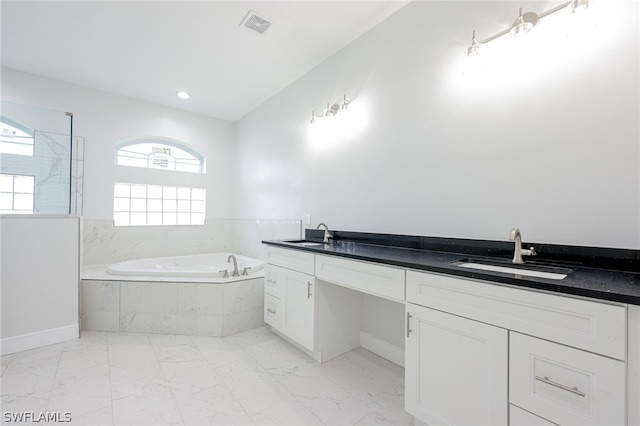 bathroom featuring tile flooring, double sink vanity, and tiled bath