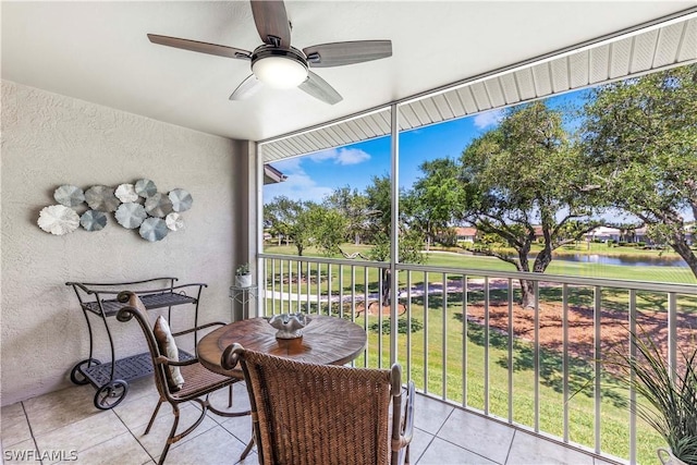 sunroom featuring a water view and ceiling fan