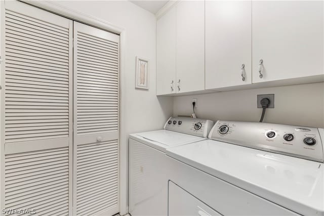 clothes washing area with electric dryer hookup, cabinets, and washing machine and clothes dryer