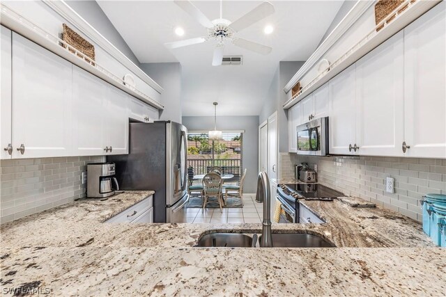 kitchen with backsplash, appliances with stainless steel finishes, vaulted ceiling, light stone counters, and white cabinets