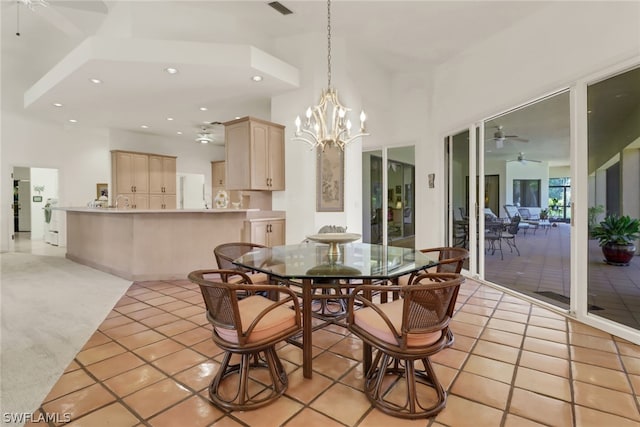 dining room with ceiling fan with notable chandelier, a high ceiling, and light tile patterned flooring