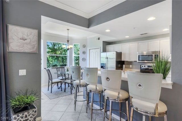 kitchen featuring white cabinets, stainless steel appliances, hanging light fixtures, and ornamental molding