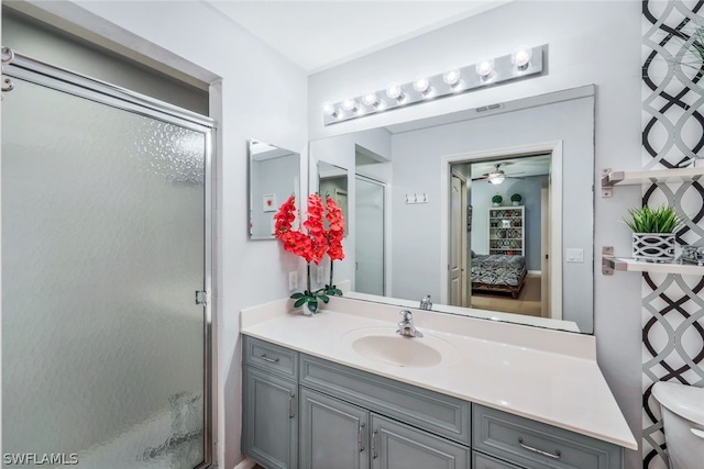 bathroom with vanity, toilet, ceiling fan, and a shower with shower door