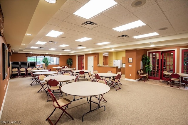 dining room with a paneled ceiling, light carpet, and french doors