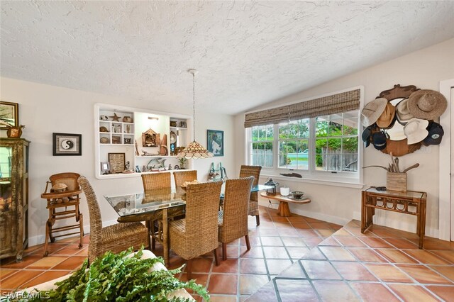 tiled dining room featuring a textured ceiling and baseboards