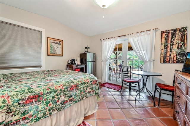 bedroom with light tile patterned floors, vaulted ceiling, freestanding refrigerator, and access to exterior