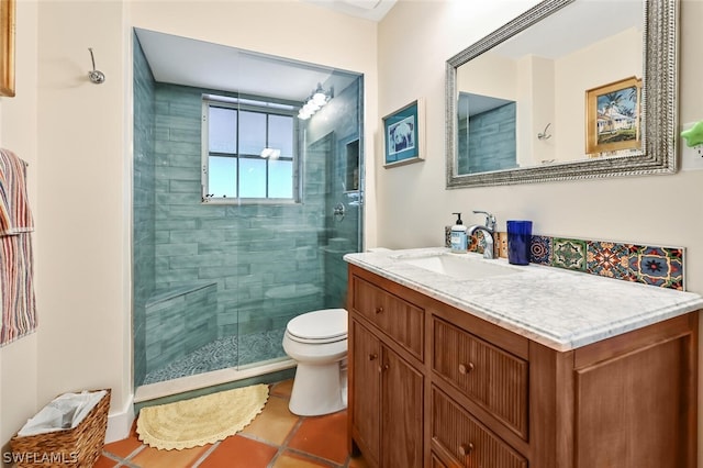 bathroom with a tile shower, vanity, toilet, and tile patterned floors