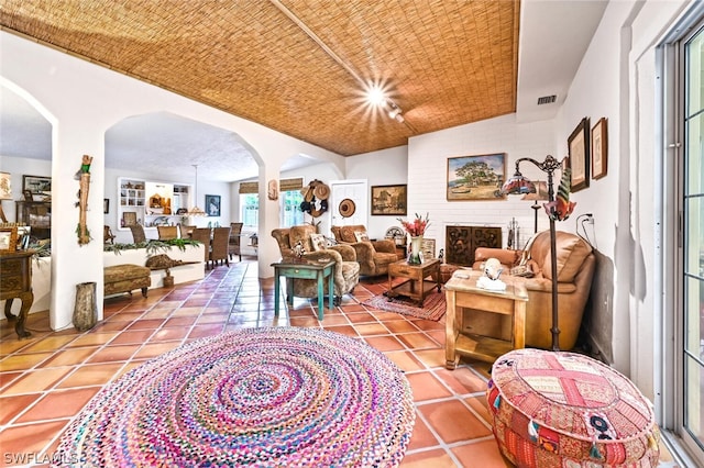 interior space featuring arched walkways, a brick fireplace, visible vents, and tile patterned floors