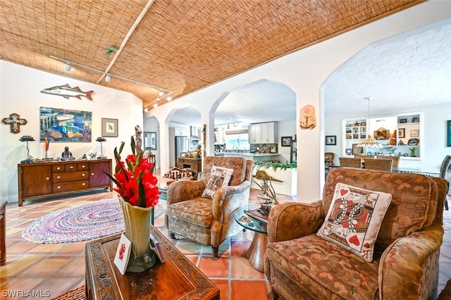 tiled living area featuring arched walkways and track lighting