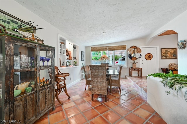 dining room featuring a textured ceiling, tile patterned flooring, and baseboards