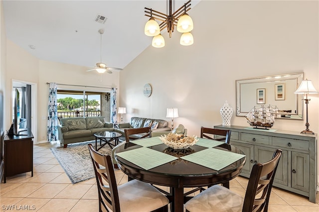 dining area with ceiling fan with notable chandelier, high vaulted ceiling, and light tile floors