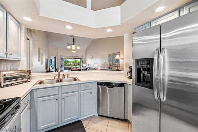 kitchen featuring kitchen peninsula, decorative light fixtures, stainless steel appliances, sink, and light tile floors