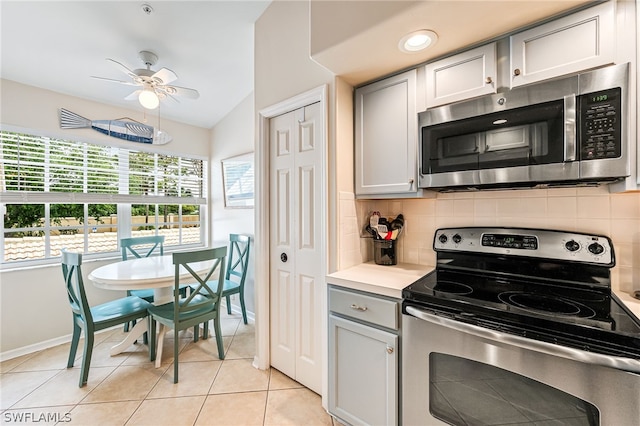 kitchen featuring appliances with stainless steel finishes, gray cabinets, ceiling fan, and backsplash