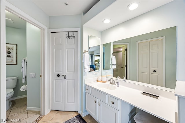 bathroom with tile flooring, vanity with extensive cabinet space, and toilet