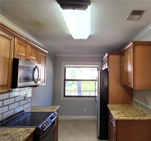 kitchen featuring light stone counters, crown molding, light tile patterned floors, appliances with stainless steel finishes, and decorative backsplash