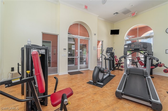 workout area with light hardwood / wood-style floors and crown molding