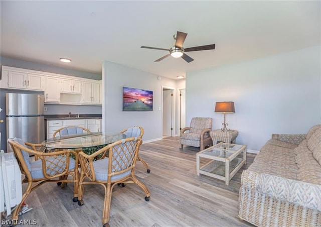 dining area featuring sink, ceiling fan, light wood-type flooring, and radiator heating unit