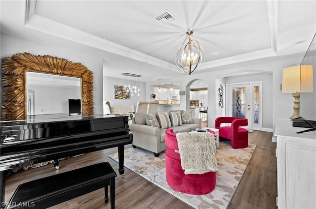 living room with a raised ceiling, hardwood / wood-style floors, and a chandelier