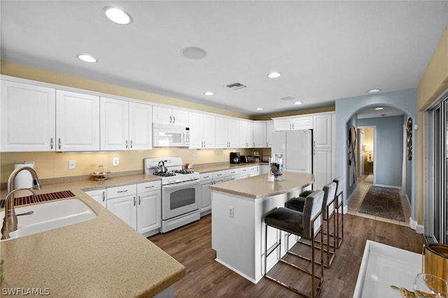 kitchen featuring a kitchen bar, white appliances, white cabinetry, and a kitchen island