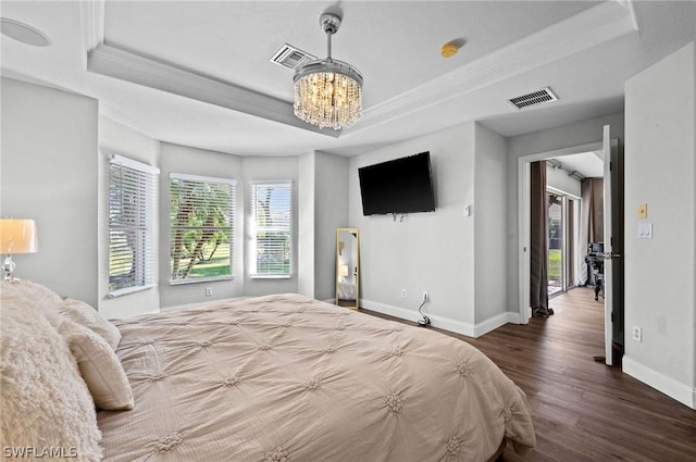 bedroom featuring a notable chandelier, dark hardwood / wood-style flooring, a raised ceiling, and ornamental molding