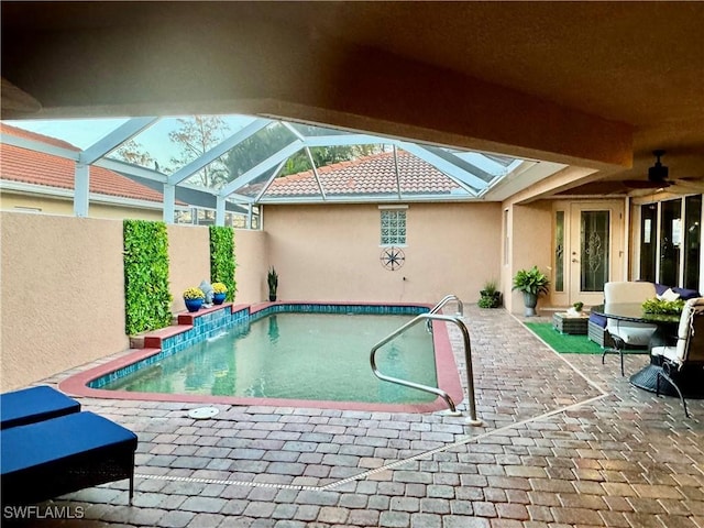 view of swimming pool with a patio, glass enclosure, and ceiling fan