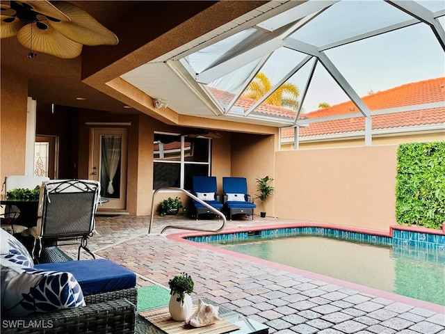 view of pool featuring glass enclosure, ceiling fan, and a patio