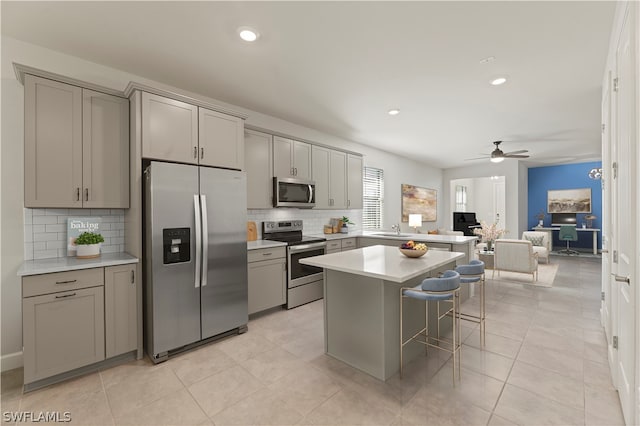 kitchen featuring ceiling fan, tasteful backsplash, stainless steel appliances, and gray cabinets