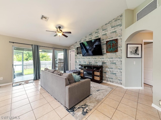 living room featuring lofted ceiling, a fireplace, ceiling fan, and light tile floors