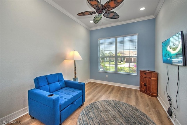 living area with ceiling fan, ornamental molding, and wood-type flooring