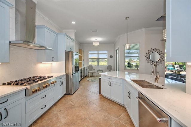 kitchen featuring appliances with stainless steel finishes, pendant lighting, sink, light stone countertops, and wall chimney exhaust hood