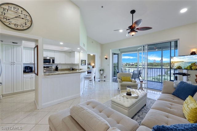 tiled living room featuring sink, a towering ceiling, and ceiling fan