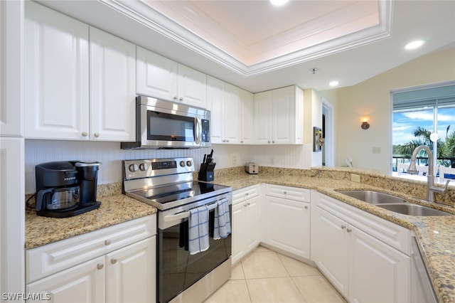 kitchen with appliances with stainless steel finishes, white cabinetry, sink, light tile patterned floors, and light stone counters