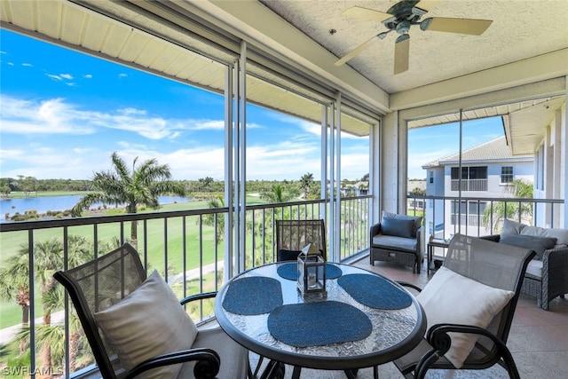 sunroom / solarium with a water view and ceiling fan