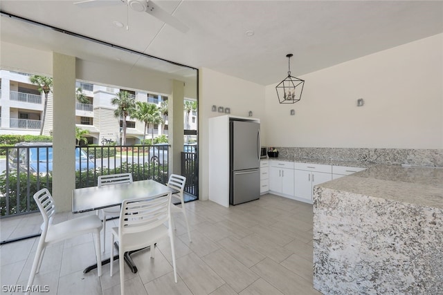 kitchen featuring hanging light fixtures, white cabinetry, ceiling fan with notable chandelier, and stainless steel fridge