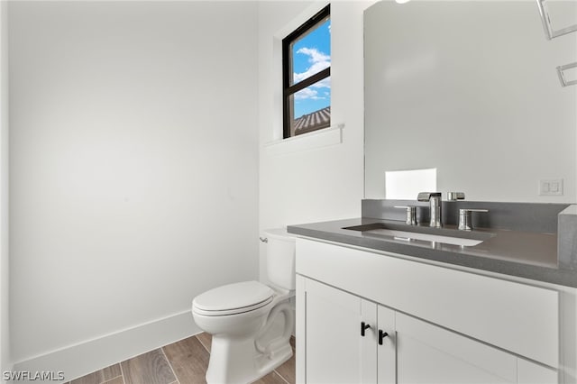 bathroom featuring wood-type flooring, vanity, and toilet