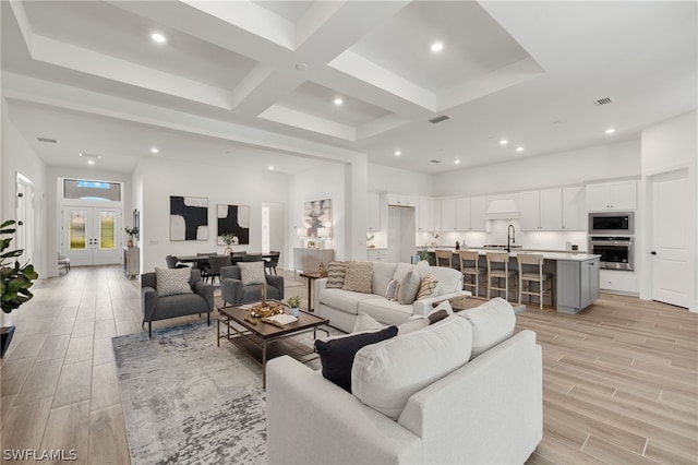 living room featuring beam ceiling, french doors, sink, coffered ceiling, and light hardwood / wood-style flooring