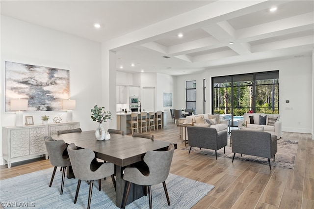 dining space with beam ceiling, coffered ceiling, and light wood-type flooring