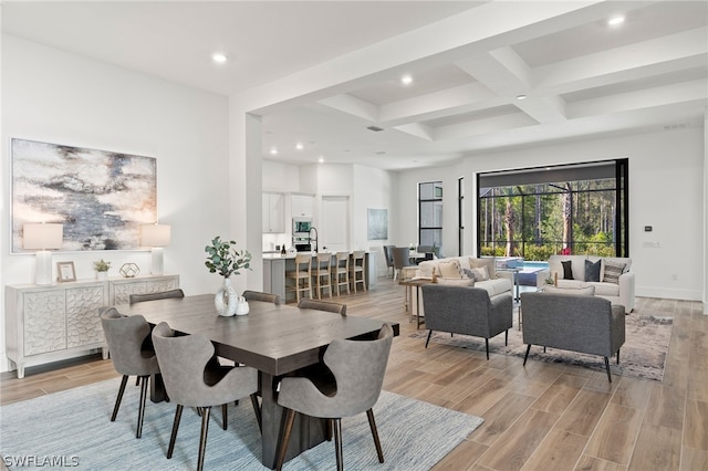 dining area with coffered ceiling, beam ceiling, and light hardwood / wood-style flooring