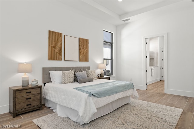 bedroom with connected bathroom and light hardwood / wood-style floors