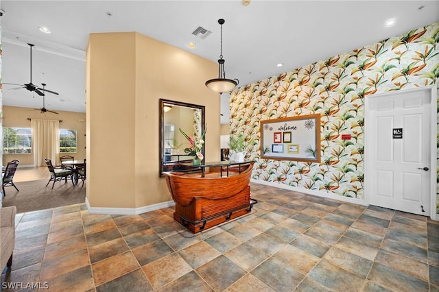 interior space with baseboards, an accent wall, visible vents, and wallpapered walls