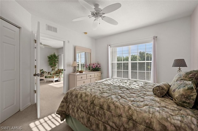 bedroom featuring a ceiling fan, visible vents, and light colored carpet