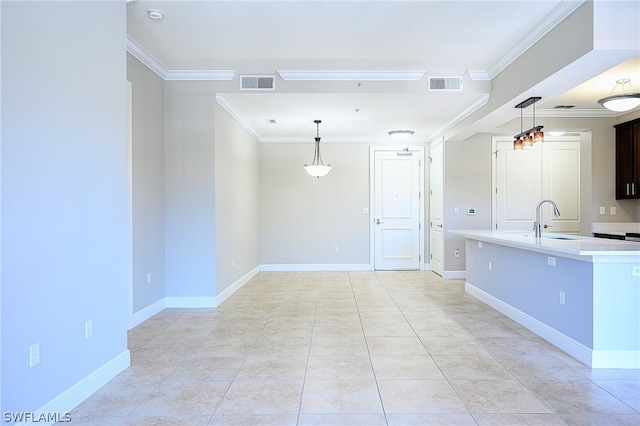 kitchen with hanging light fixtures, light tile flooring, sink, and crown molding