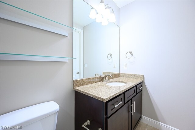 bathroom featuring tile floors, vanity, toilet, and a notable chandelier